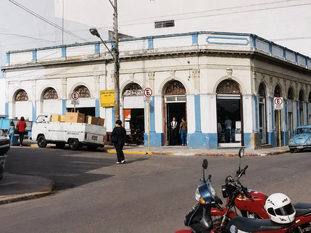 A fachada do prédio em cores, com o movimento da rua
